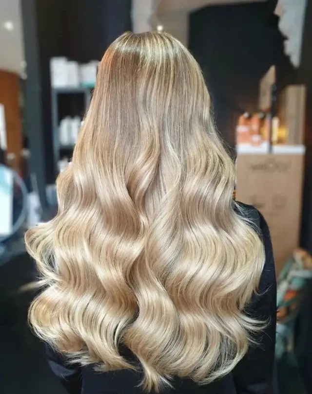 Back view of long, shiny platinum blonde hair styled into soft, structured Hollywood waves