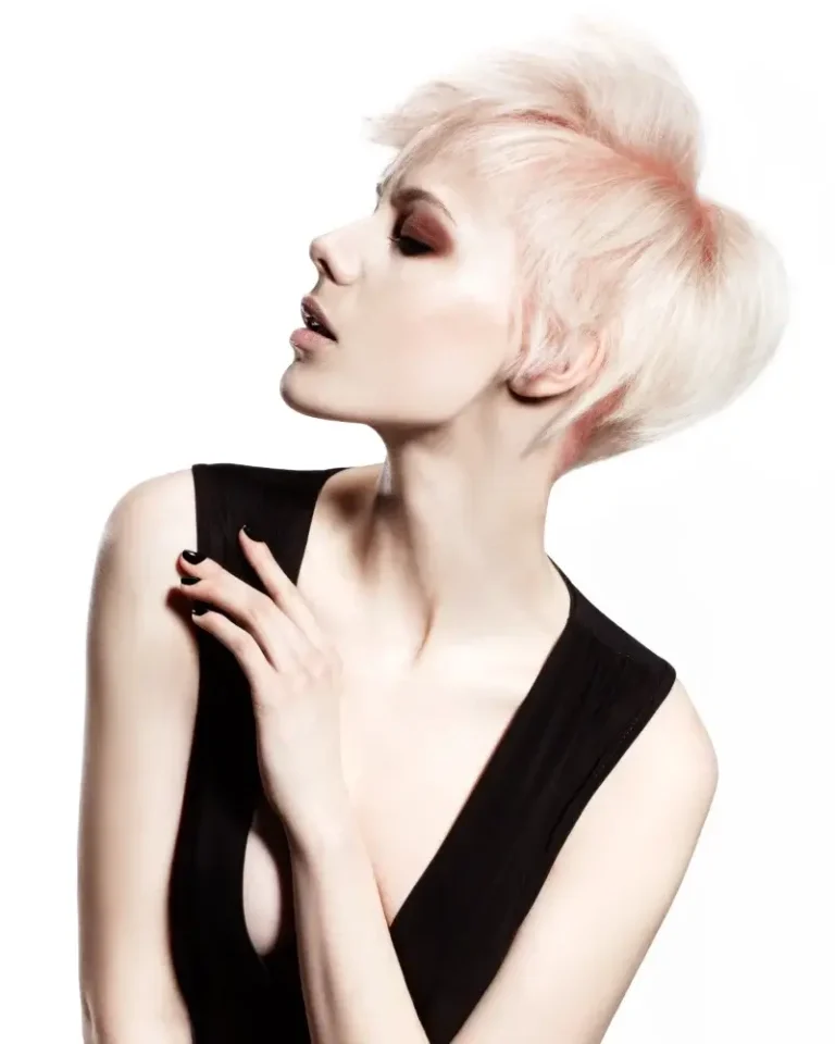 Model in profile with a short, textured platinum pastel-blonde updo and soft pink undertones, wearing a sleeveless black top