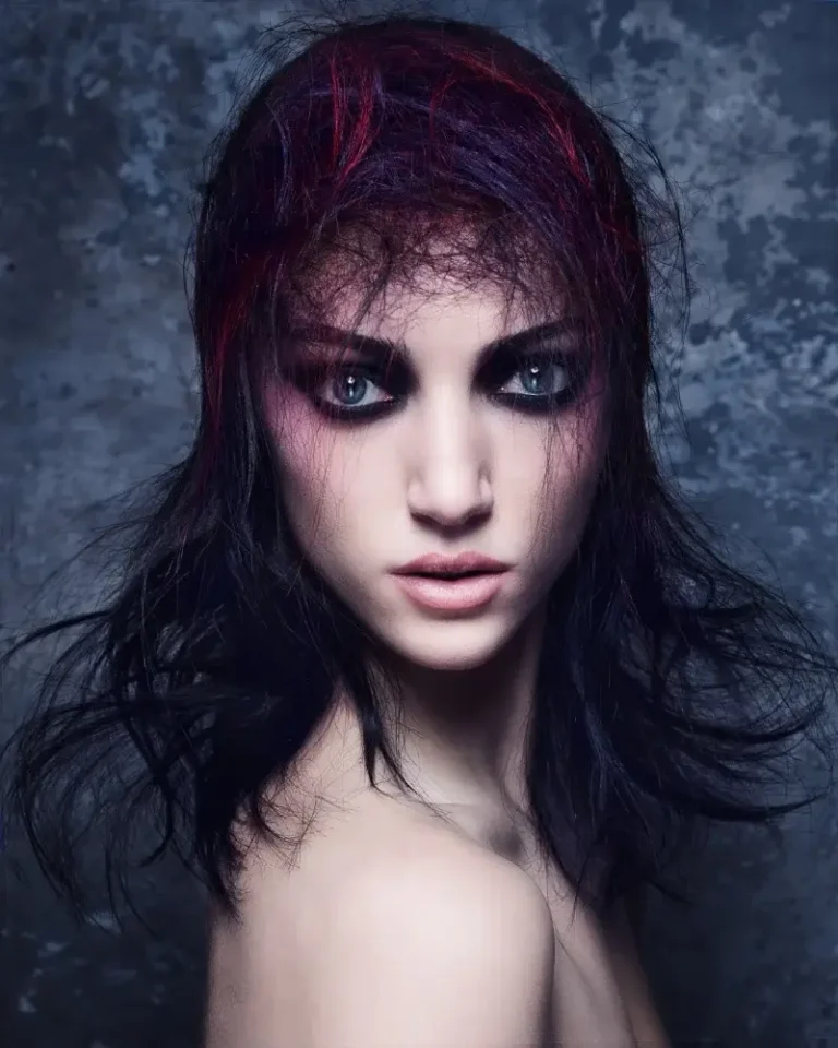 Model with layered dark hair featuring magenta highlights and thin, textured micro-bangs swept over the forehead