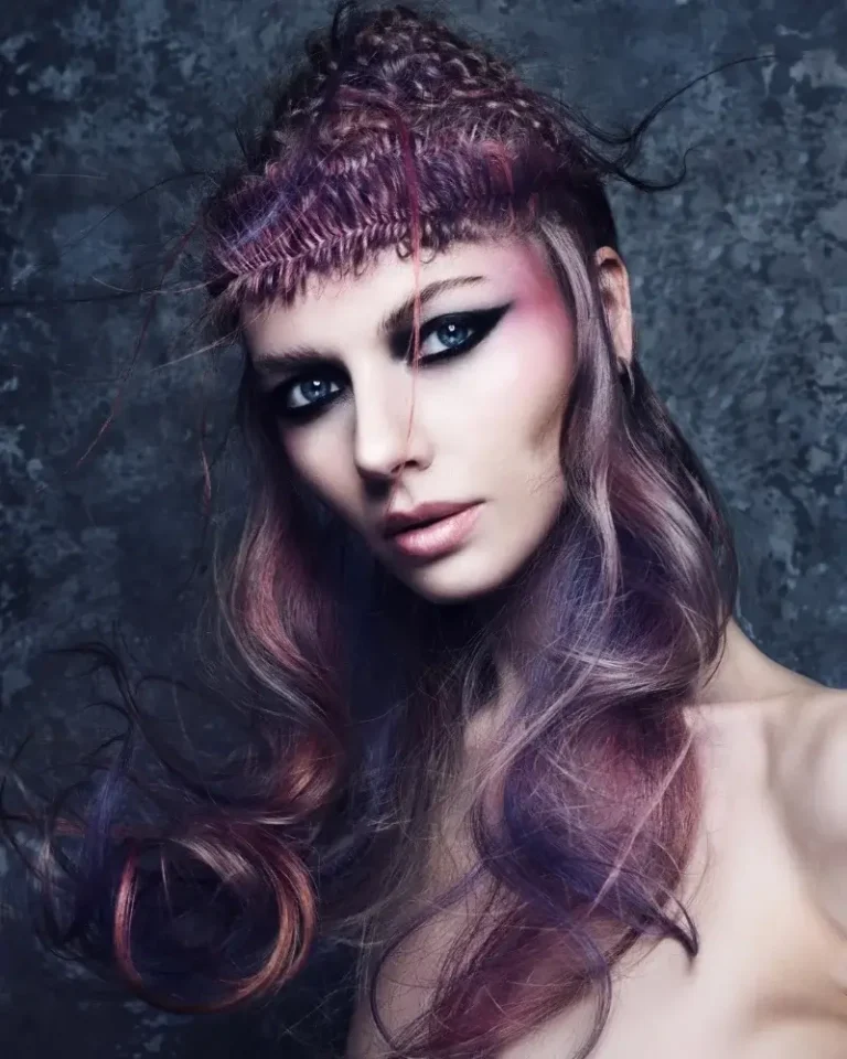 Model featuring intricate braided micro-fringe with long, wavy hair blending purple, pink, and ash tones