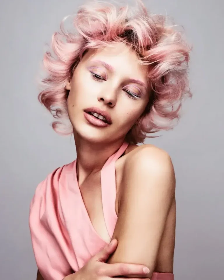 Model showcasing short, piecey pastel pink waves styled with soft volume and short bangs