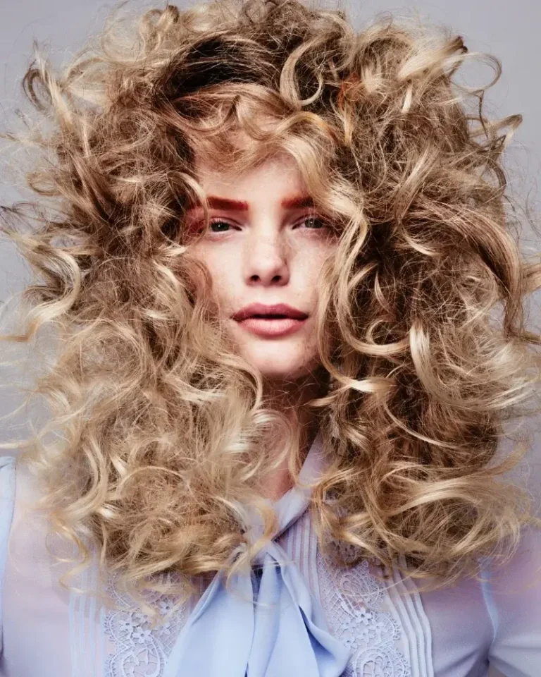 Model with voluminous, tight blonde curls styled into a full afro shape