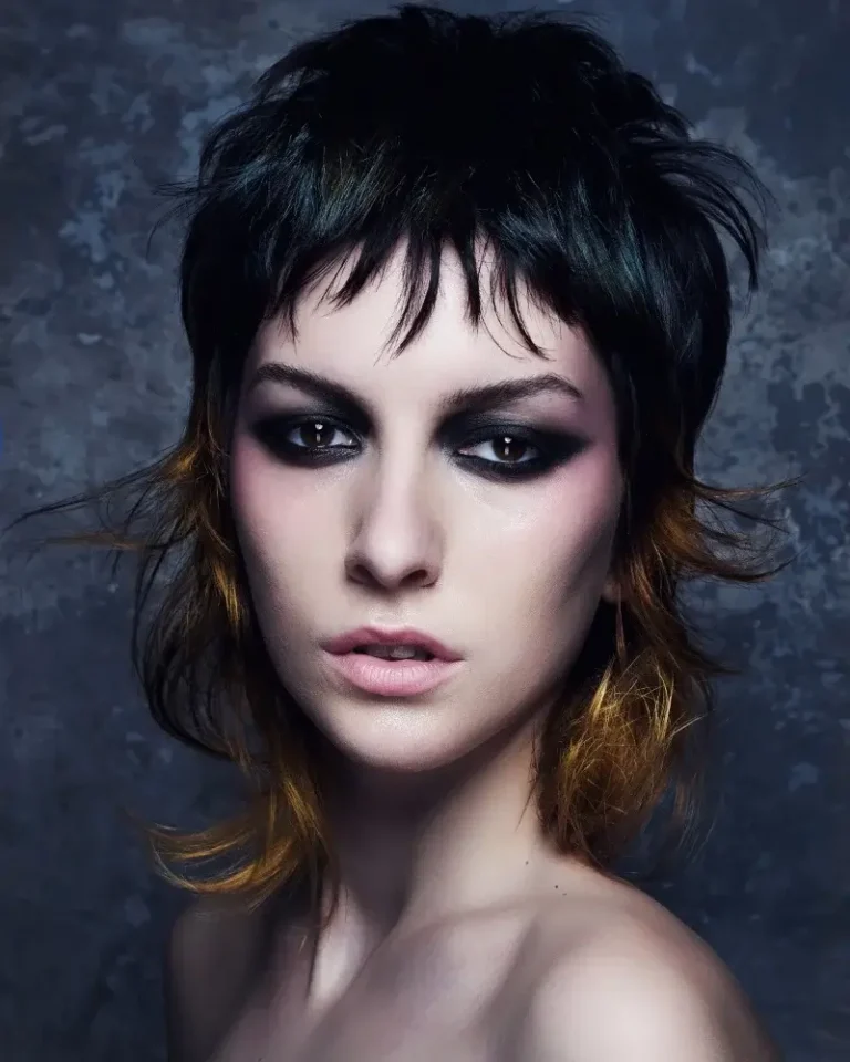 Model with a dark shag cut featuring short piecy bangs and warm amber tips